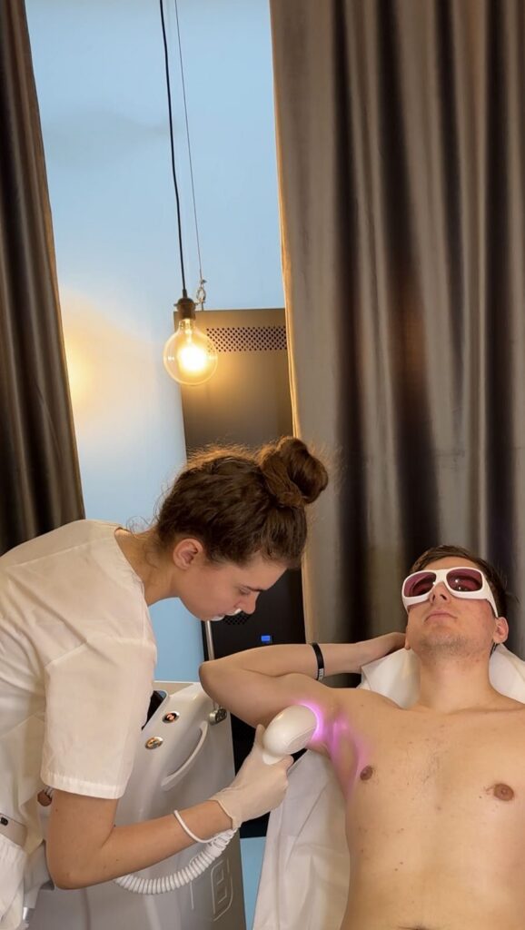Kosmetolożka wykonuje depilację laserową pach u mężczyzny